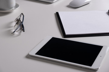 Tablet with writing paper with pen on white table