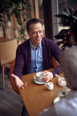 Middle aged elegant smiling have meeting in cafe