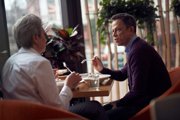 Aged man and woman talking while having dinner
