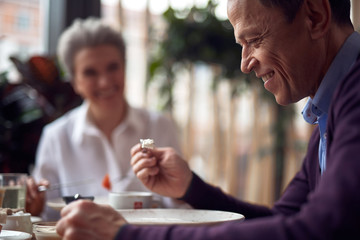 Smiling man having dinner in cafe with woman