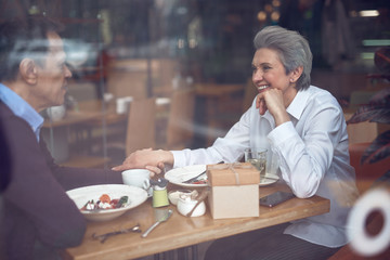 Happy elegant aged couple enjoying meeting in cafe