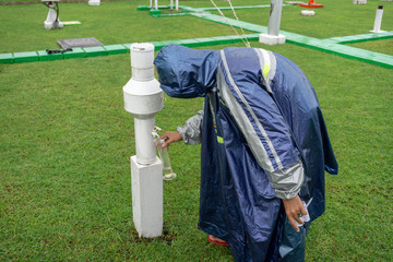 BALI/INDONESIA-DECEMBER 21 2017: A meteorological observer checks the rain meter at meteorology...