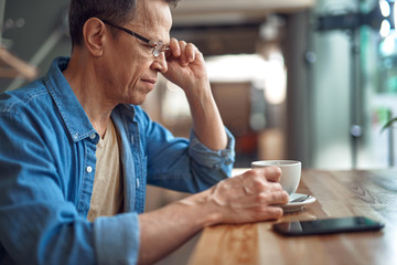 Casual style aged man sitting in cafe with coffee