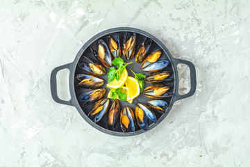 Seafood mussels with lemon and parsley in black metal pan