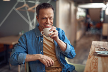 Happy mature man sitting in cafe with coffee