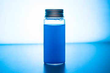 Glass jar with colored liquid on a blue background