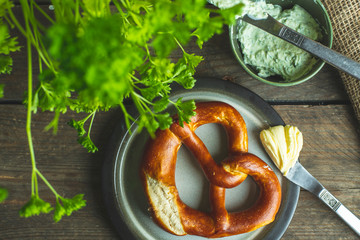 german pretzel with butter on a rustic wooden table