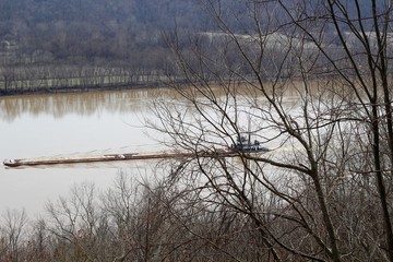 The barge vessel going up the river though the trees.