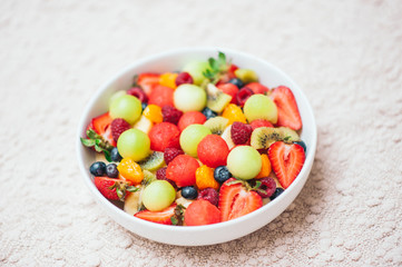 Healthy fruit spring salad. Healthy diet concept. Delicious fresh berries in bowl. Selective focus. Top view. Colourful fruits mixed in homemade salad. Nutrition concept