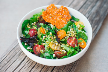 Healthy food concept. Fresh sald of cherry tomatoes, mung bean, carrot chips and flat bread on wooden background. Green vegetable salad for dinner