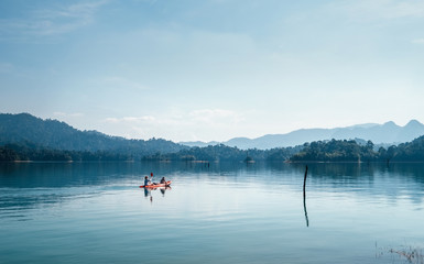Fototapeta na wymiar Mother and son floating on kayak together on calm water of Cheow Lan lake in Thailand