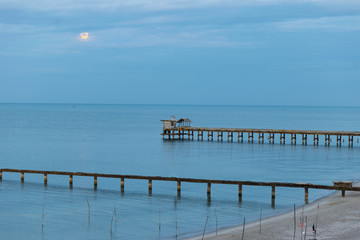 Fototapeta na wymiar Beach, Bridge and The moon is rising at .Nim Seng Beach, Songkhla, Thailand.