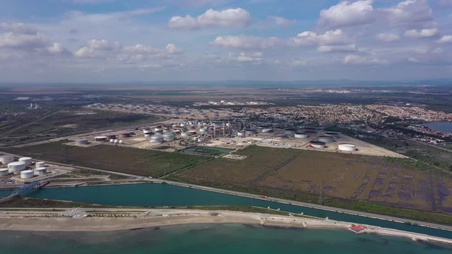 Aerial left to right traveling over a industrial complex gas and oil storage tanks Fos sur mer sunny day France