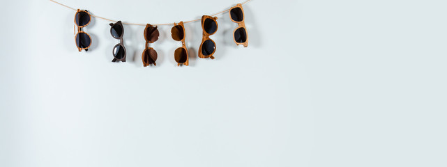 Sunglasses sale concept. Different sunglasses hanging on the rope on blue background. Fashion...