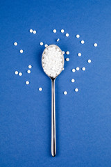 Sugar-replacing tablets with a spoon on a blue background