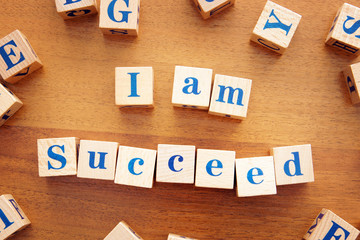 I am succeed. Conceptual image with the text made from wooden cubes on a desk
