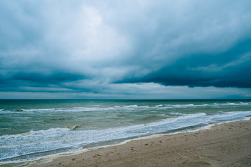 Fototapeta na wymiar Windy storm beach seashore seaside sea waves dark clouds