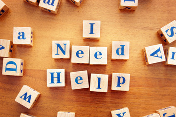 I need help. Conceptual image with the text made from wooden cubes on a desk