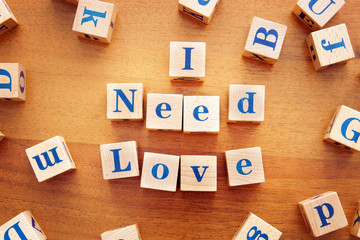 I need love. Conceptual image with the text made from wooden cubes on a desk
