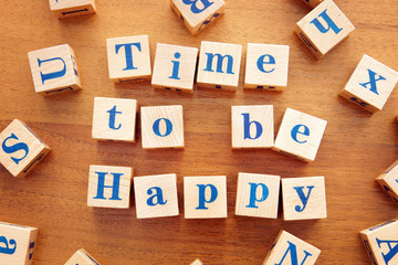Time to be happy. Conceptual image with the text made from wooden cubes on a desk