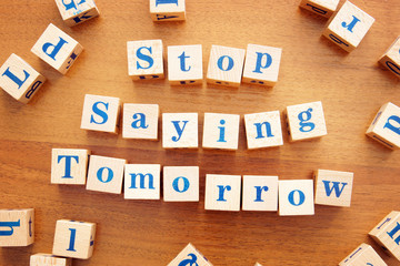 Stop saying tomorrow. Conceptual image with the text made from wooden cubes on a desk