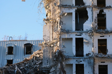 Demolished destructed building ruins. Demolition site in european city. Ruined house on a bright blue sky on a sunny day.