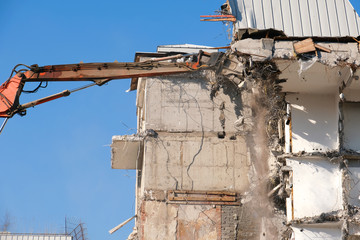 Building demolition with hydraulic excavator. Demolished destructed house ruins in european city on...