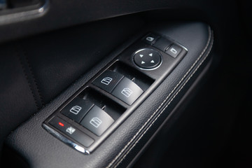 Obraz premium The interior of the car with a view of the driver door panel and windows switch buttons with light gray trim