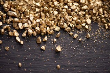 Fototapeta premium Abstract golden crushed gravel dust on stone black background