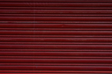 Close up of a roller shutter door, plastic red texture background