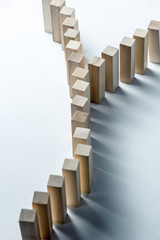 A long curved line of wooden cubes is divided into two, as a symbol of a queue, a competition for a position or a team, on an uneven white background. Vertical frame