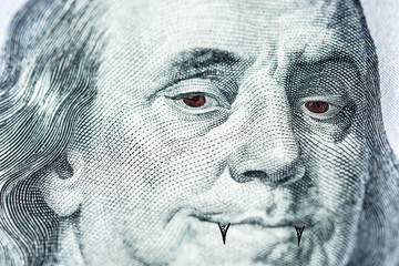 Benjamin Franklin's face with red eyes and fangs like a vampire, a symbol of a bloodsucker, pumping out money, inflation, dependence on currency, close-up