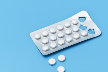 One pack of pills and next are three pills squeezed out on a blue background