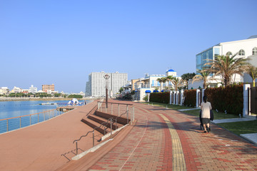 유모차를 끌고 해안가 산책로를 걷는 여성 (일본 오키나와 차탄 미하마)