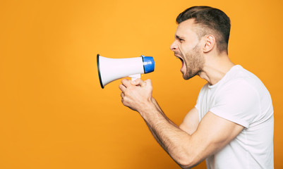 Screaming at full voice. Side view portrait with megaphone in a hand of emotional, sporty boy who...