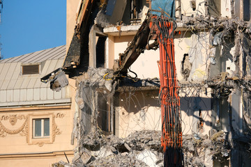 Building demolition with hydraulic excavator. Demolished destructed house ruins in european city on...