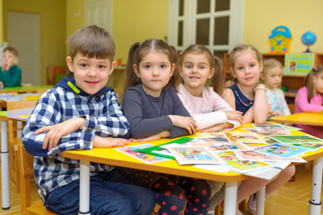 a group of children sit at the desk in a lesson in a kindergarten