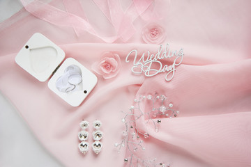 Obraz na płótnie Canvas decorative fabric flowers, bridal jewelry on pink chiffon on white paper background - top view