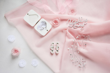 decorative fabric flowers, bridal jewelry on pink chiffon on white paper background - top view