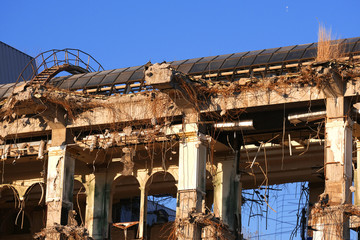 Demolished destructed building ruins. Demolition site in european city. Ruined house on a bright blue sky at sunset