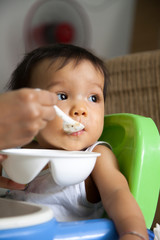 Mother is feeding baby in a house