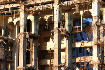 Demolished destructed building ruins. Demolition site in european city. Ruined house on a bright blue sky at sunset