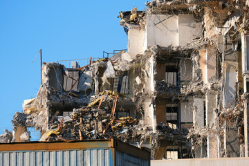 Demolished destructed building ruins. Demolition site in european city. Ruined house on a bright blue sky on a sunny day.