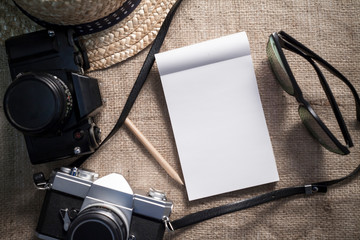Notebook,cameras,sunglasses and a hat for travel