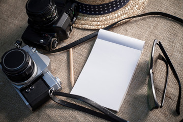 Notebook,cameras,sunglasses and a hat for travel