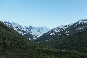 Fototapeta na wymiar Green landscape with alpine meadow and snowcapped mountain peak in the Caucasus in Georgia