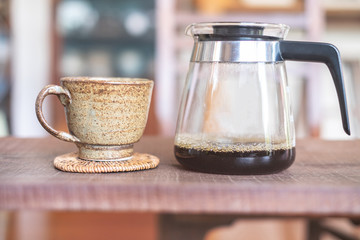 A cup of coffee drip and beaker with hot coffee on wooden table 
