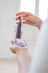 Woman hands holding lilac mala beads for meditation