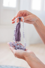Woman hands holding lilac mala beads for meditation