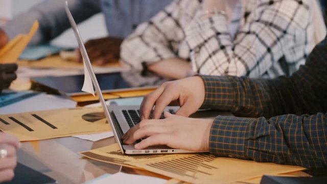 Close-up shot of male software developer hands working behind office table with laptop at hackathon meeting event.
